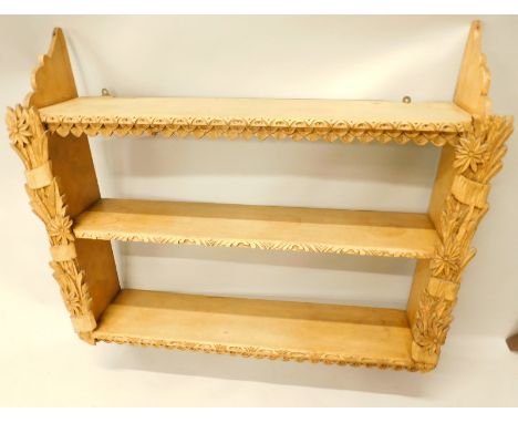 An early 20thC hanging shelf, in three sections, broken by carved wheat and flower head supports, 92cm high x 88cm wide x 22c