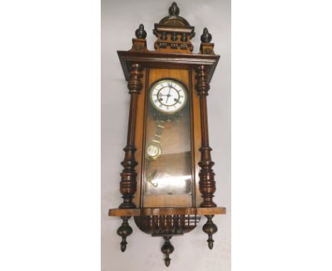 A late 19thC Vienna wall clock, with later shaped pediment, the walnut case with ebonised pilasters, flanking an enamel dial 