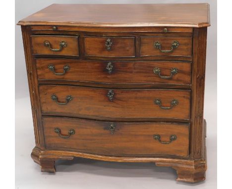 A mahogany serpentine fronted chest of drawers in George III style, the top with a moulded edge above a brushing slide, three