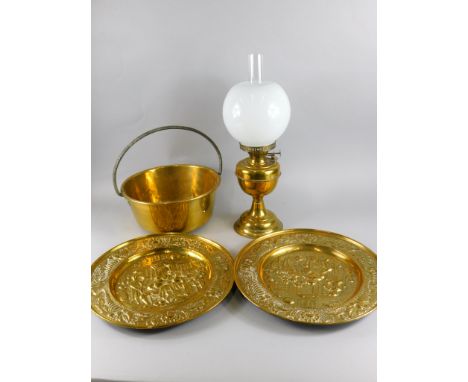 A collection of metalware, to include a brass preserve pan with iron handle, large pressed brass chargers and an oil lamp