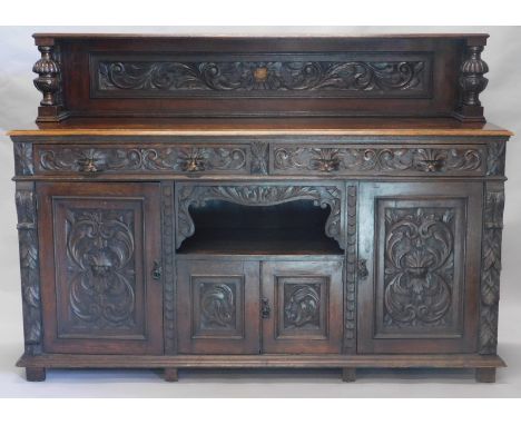 A late 19thC oak sideboard, the top with heavy pillars holding an open shelf above a sub section with heavily carved drawers 