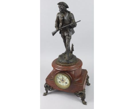 A French spelter and rouge marble mantel clock, the figural surmount titled "Le Chasseur Parbouret", the part cylindrical bas