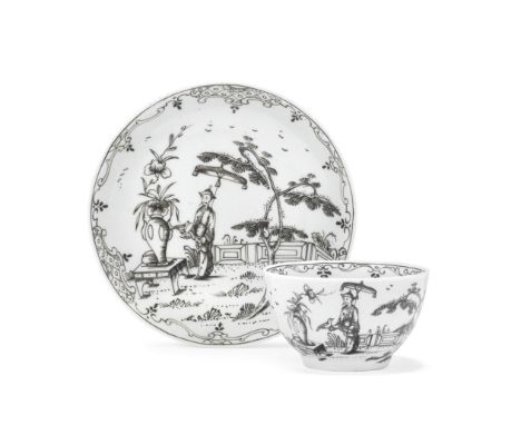 A Worcester teabowl and saucer, circa 1756-58 Pencilled in black enamel with a Chinese figure holding a bird in one hand and 