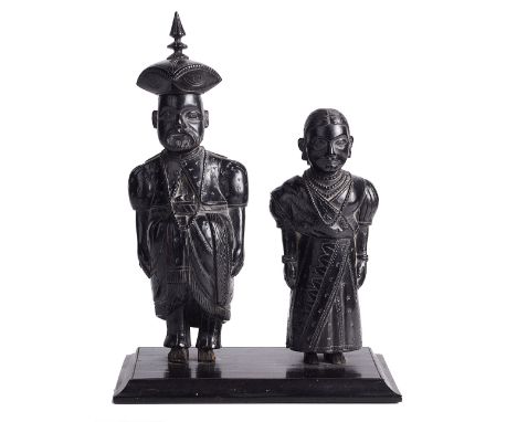 ~AN EBONY MODEL OF A KANDYAN ROYAL COUPLE, SRI LANKA, EARLY 20TH CENTURYboth wearing traditional headdress, the male with pot
