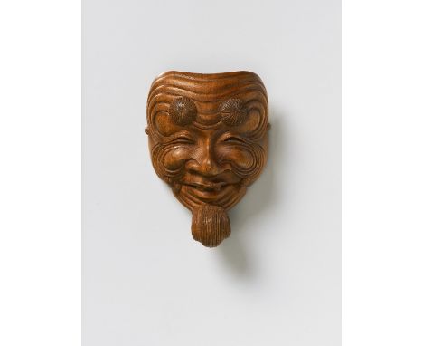 A JAPANESE MASK NETSUKE OF OKINA, BY SHUGETSU, 19TH CENTURYpale boxwood, the himotoshi bar carved as silk cords, signed ‘Shug