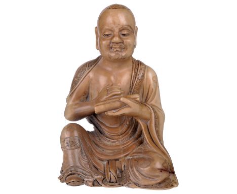 ‡ A CHINESE SOAPSTONE FIGURE OF A LUOHAN, 19TH CENTURYthe beige soapstone figure carved seated and holding a scroll in his le