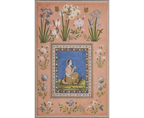 ‡ AN INDIAN WOMAN, QAJAR, PERSIA, 19TH CENTURYgouache with gold on paper, laid on an album page, the woman seated on a charpo