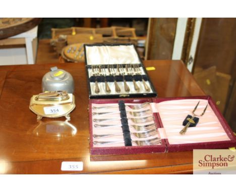 A pewter inkwell, a retro cigarette lighter, a cased set of plated cake forks and another similar