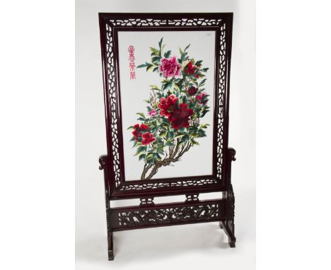 A 20th Century carved hardwood screen having painted glass central panel with floral design.