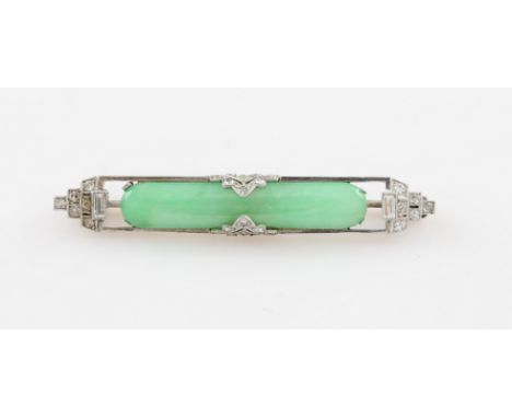 An Art Deco style jade brooch, set with a central elongated piece of jade, set to each side with stepped design set with roun