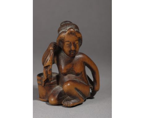 A mid 19th century Japanese netsuke from Edo period. Not signed. In carved wood portraying a kneeling 'Ama' or woman drying h