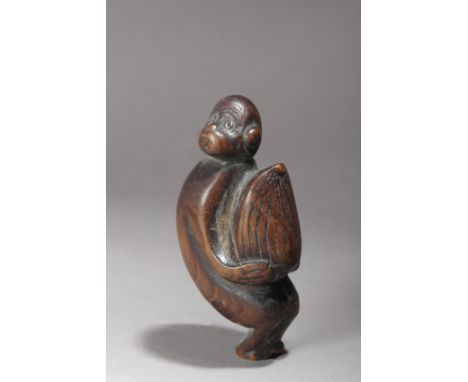 A 19th century Japanese netsuke. Not signed. In carved wood portraying a standing monkey holding a gigant chestnut, 5,6x3,1x2