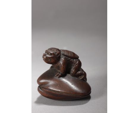 A 19th century Japanese netsuke. Signed Gyokokyu. In carved wood portraying a "Kappa" on a gigant clam, 3,22x3,73x3 cm. 7,29 