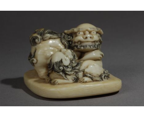 A mid 19th century Japanese netsuke from Edo period. Not signed. In carved elephant ivory portraying two 'Shishis' on a pedes