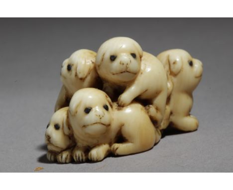 A mid 19th century Japanese netsuke from Edo period. Signed Toko. In carved elephant ivory portraying a group of five puppies