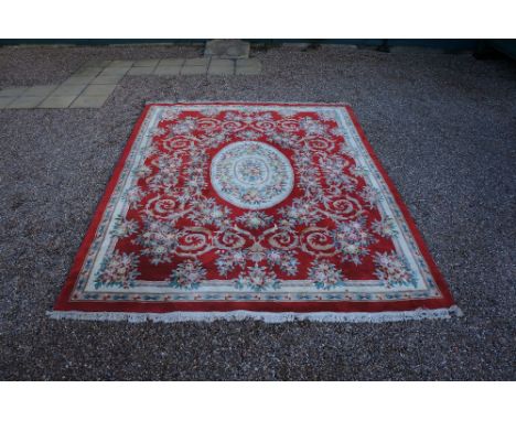 A modern Chinese sculpted carpet worked with floral sprays and scrolling leafage on a rust red ground, ivory foliate borders,