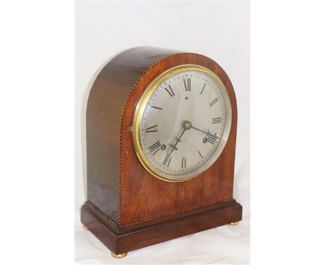 An Edwardian mahogany cased mantel clock of arched form inlaid with parquetry stringing the silvered dial with Roman numerals