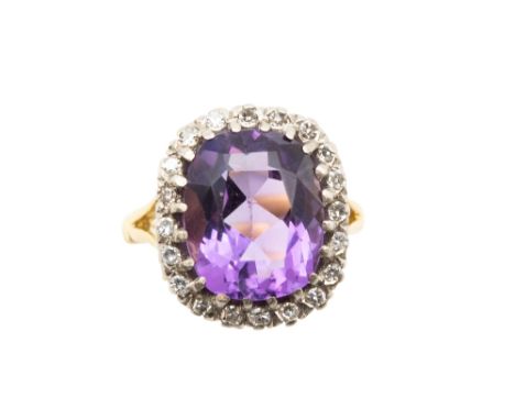 AN AMETHYST AND DIAMOND CLUSTER RINGThe cushion-cut amethyst, within a surround of single-cut diamonds, between scrolling ope
