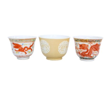 THREE CHINESE PORCELAIN WINE CUPS, the first brown-glazed and moulded with four shou symbols, 5.5cm high; the second painted 