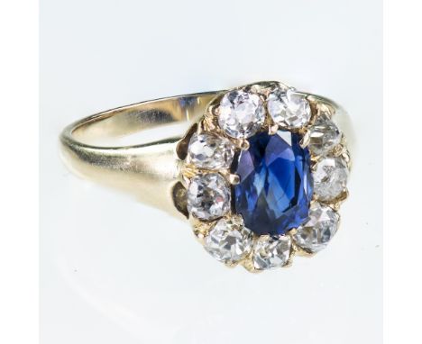 AN 18CT YELLOW GOLD SAPPHIRE AND DIAMOND CLUSTER RINGThe oval cut sapphire within a surround of nine old brilliant cut diamon