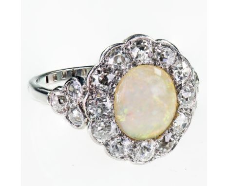 AN 18CT WHITE GOLD AND PLATINUM OPAL AND DIAMOND CLUSTER RINGThe round cabochon cut opal within a scalloped edge surround of 