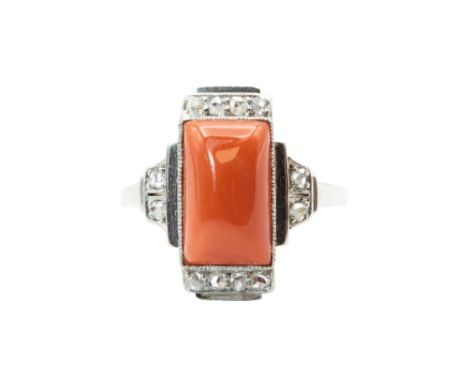 A CORAL AND DIAMOND DRESS RING, CIRCA 1925  The rectangular cabochon coral corallium rubrum, within a geometric surround set 