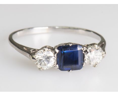 A SAPPHIRE AND DIAMOND RINGThe square cut sapphire between two brilliant cut diamonds, between pierced shoulders on tapering 