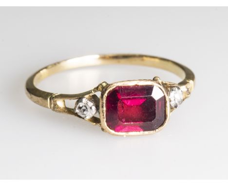 A GARNET AND DIAMOND RINGThe rectangular cut garnet in closed back setting between two old cut diamond highlights, between op