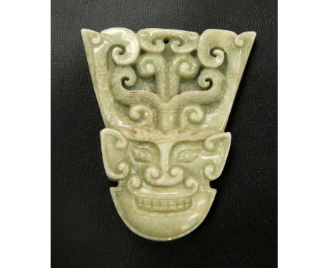 A CHINESE JADE PENDANT, carved with a mask. 7.6cm by 6.4cm