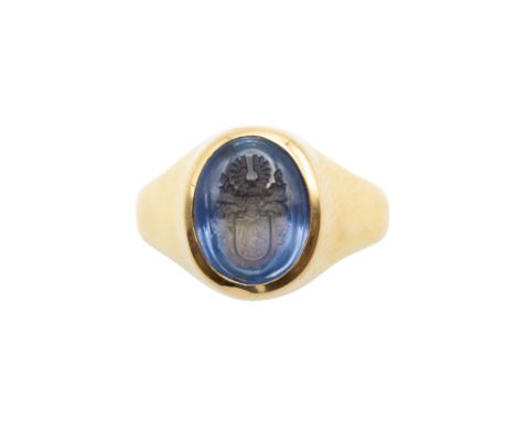 A SAPPHIRE INTAGLIO RING The oval plaque incised with a crest, in a polished mount, ring size R.  Accompanied by a gemmologic