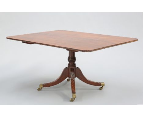 A REGENCY MAHOGANY TILT-TOP BREAKFAST TABLE, the rectangular top with reeded edge, raised on a ring-turned and tapering stem 