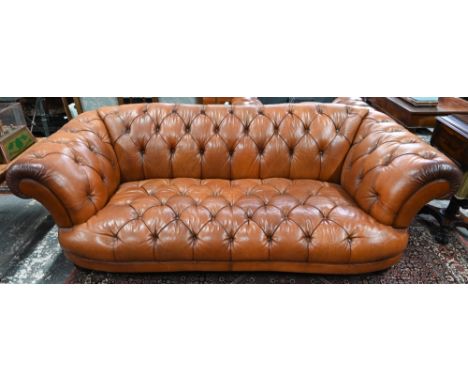 A large contemporary antiqued buttoned brown leather Chesterfield style sofa and matching armchair, raised on bulbous moulded