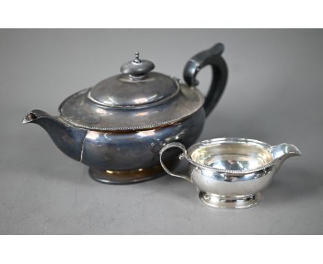 An ovoid silver bachelor teapot with beaded rim, composite handle and finial, on spread foot rim, to/w the matching milk jug,