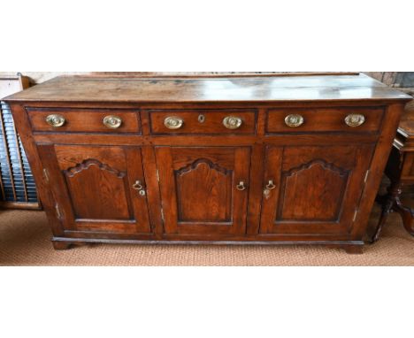 An 18th century oak and elm low dresser base with three drawers over three fielded panel doors, with brass fittings, raised o