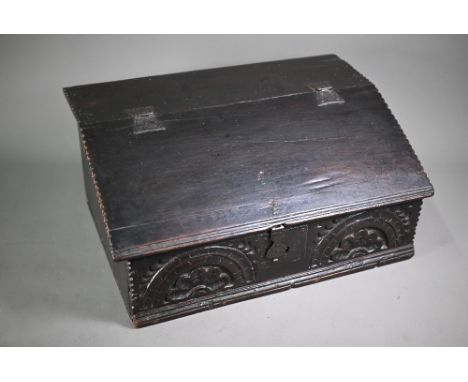 A 17th century oak bible box, the iron hinged slope enclosing three drawers over a storage well, the frieze lunette carved an