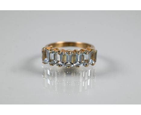 An aquamarine half eternity ring set with seven baguette cut pale aquamarines in yellow metal setting stamped 375, size J  