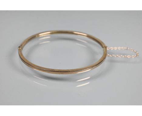 A narrow oval half hinged bangle fitted with safety chain, unmarked and untested, approx 4.9g  Bruised