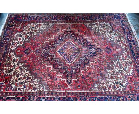 A Persian Heriz carpet of traditional design, the red ground centred by a medallion in reds and blues, 2nd half 20th century,