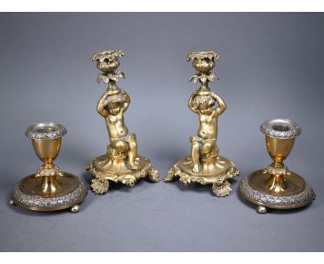 A pair of Rococo style gilt bronze candlesticks, modelled as seated cherubs raised on organic form bases, 20 cm h (2)  