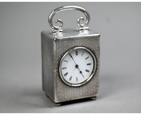 A late Victorian silver boudoir clock with hinged top handle, engine-turned decoration and bun feet; JTC Swiss movement, case