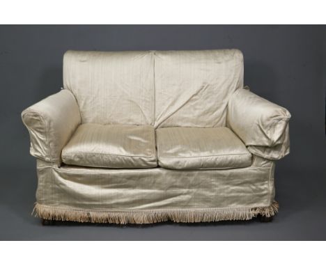 A traditional two-seat sofa with gold silk loose covers over patterned undercloth, raised on hip carved ball and claw front l