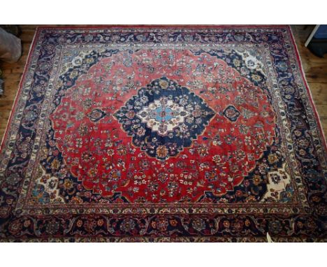 An Indo-Persian Kashan carpet, the red ground centred with a blue ground floral medallion  Good pile, some sun fading to appr