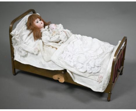 A French automaton bisque-head Armand Marseille girl doll, in a brass bed, 38 cm wide overall; she sits up, kisses baby and l
