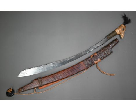 A Dyak sword, Mandu, the blade with brass inlay and pierced decoration to edge, the carved bone hilt within a part carved sca