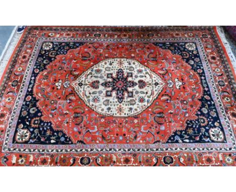 A hand-made Persian Heriz carpet, centred by a camel ground oval tablet on salmon-red ground, 347 cm x 257 cm  good even pile