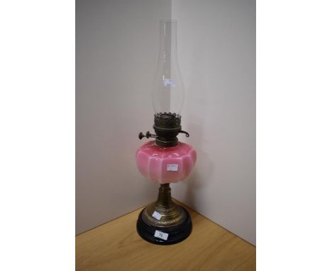 A Victorian brass and coloured glass oil lamp, of traditional design with opaque graduated cranberry tinted reservoir, the tw