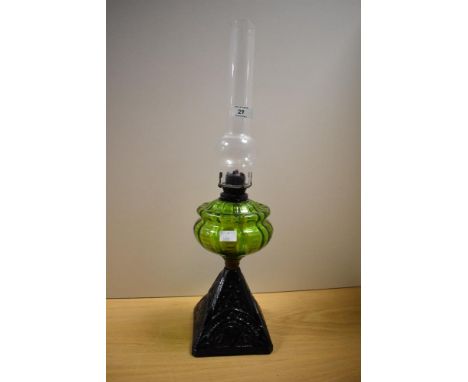 A Victorian oil lamp, with moulded green glass reservoir and painted cast iron base, measuring 55cm tall