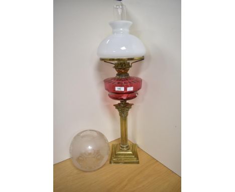 An early century brass and cranberry glass oil lamp, of Corinthian column form with stepped square base and cranberry reservo