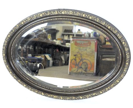 A late Victorian oval bevelled wall mirror, the mahogany frame decorated with scrolling foliage, height 63cm