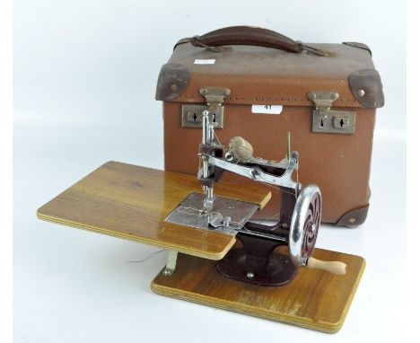 A mid-century red and chrome Essex miniature sewing machine, on a wooden base, with instruction manual, in a vintage case